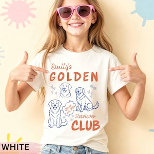 May include: White t-shirt with the text "Emily's GOLDEN Retriever CLUB" in orange. The shirt features three line drawings of golden retrievers and the name "Oliver est. 2024". The shirt is being modeled by a person wearing pink sunglasses.