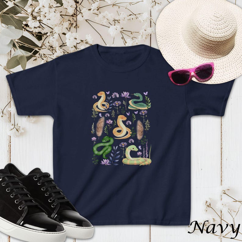 Puede incluir: Camiseta azul marino con un estampado colorido de serpientes y flores. La camiseta tiene manga corta y cuello redondo.