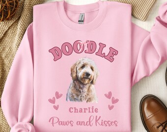 May include: Pink sweatshirt with the text "Doodle" in a pink arch, a doodle dog illustration, the name "Charlie" and the text "Paws and Kisses".