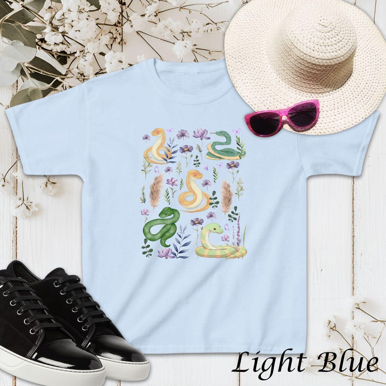 Puede incluir: Camiseta azul claro con un dise&ntilde;o de acuarela de serpientes verdes y amarillas y flores.