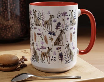 May include: White ceramic mug with a red rim and handle. The mug features a repeating pattern of Whippet dogs and purple flowers on a white background.