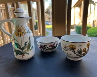 Peut inclure: Une cruche en céramique blanche avec un motif de fleur jaune, une tasse à thé assortie avec une anse et une tasse à thé sans anse. La cruche a un bord marron et un couvercle. Les tasses à thé ont des motifs floraux et des bords marron.
