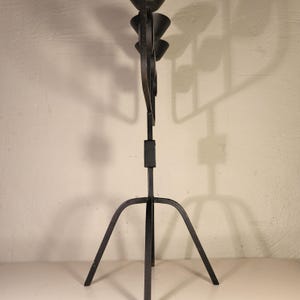 May include: Black metal candle holder with a tripod base and five candle cups. The candle holder is made of wrought iron and has a rustic, vintage look.
