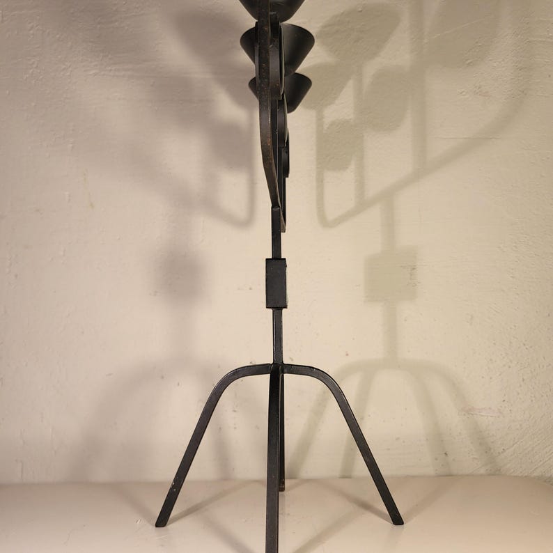 May include: Black metal candle holder with a tripod base and five candle cups. The candle holder is made of wrought iron and has a rustic, vintage look.