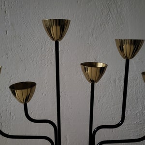 May include: A black metal candelabra with six gold candle holders. The candelabra has a modern design with curved arms.