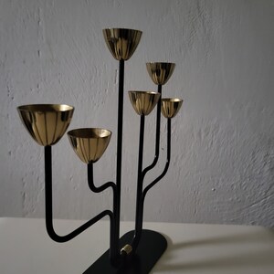May include: A black metal candelabra with five gold candle holders. The candelabra has a modern design with curved arms.