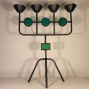 May include: A black metal candelabra with five candle holders and green glass accents. The candelabra has a tripod base.