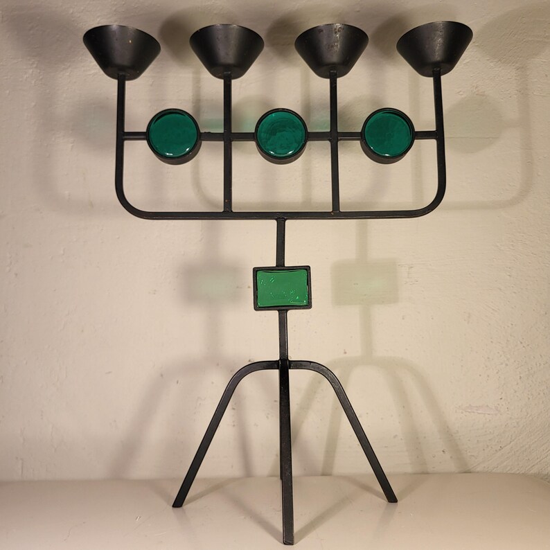 May include: A black metal candelabra with five candle holders and green glass accents. The candelabra has a tripod base.