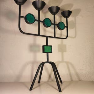 May include: A black metal candelabra with five candle holders and green glass accents. The candelabra has a tripod base.