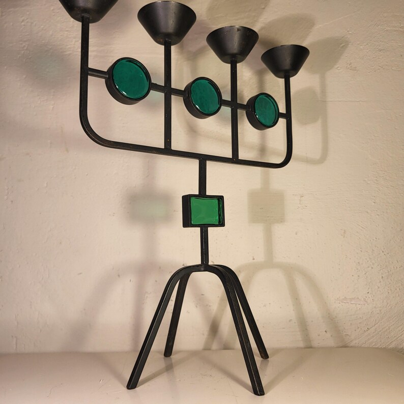 May include: A black metal candelabra with five candle holders and green glass accents. The candelabra has a tripod base.