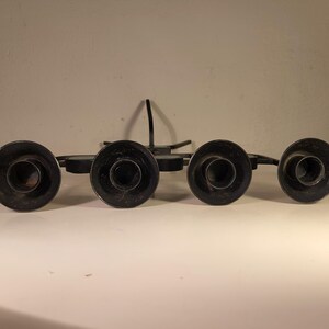 May include: Black metal candle holder with five candle cups. The holder has a starburst design and is made of wrought iron.