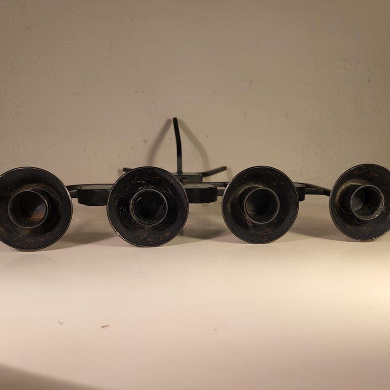 May include: Black metal candle holder with five candle cups. The holder has a starburst design and is made of wrought iron.