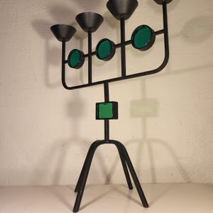 May include: A black metal candelabra with five candle holders and green glass accents. The candelabra has a tripod base.