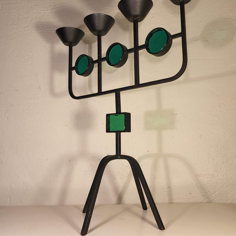 May include: A black metal candelabra with five candle holders and green glass accents. The candelabra has a tripod base.