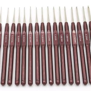 May include: Set of 17 crochet hooks with a burgundy finish. The hooks are labelled with their size in millimetres, ranging from 0.5 mm to 2.50 mm.
