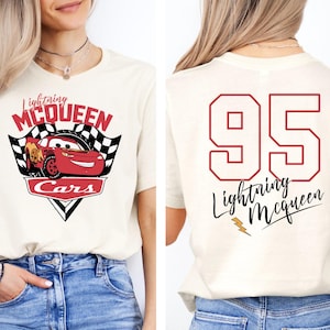 May include: White t-shirt with a red cartoon race car and the text "Lightning McQueen Cars" on the front. The back of the shirt has the number "95" and the text "Lightning McQueen" in black.