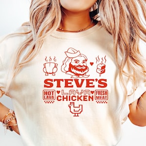 May include: A white t-shirt with a red graphic design that says "Steve's Hot Lava Chicken" with a cartoon chef and chicken illustration.