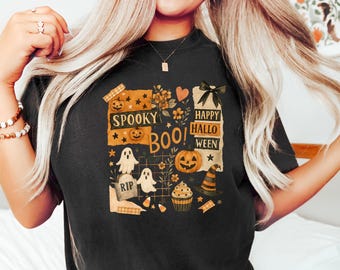 Puede incluir: Camiseta negra con un diseño de Halloween. El diseño incluye calabazas, fantasmas, un sombrero de bruja y las palabras "Spooky Boo! Happy Halloween". El diseño es naranja, blanco y negro.