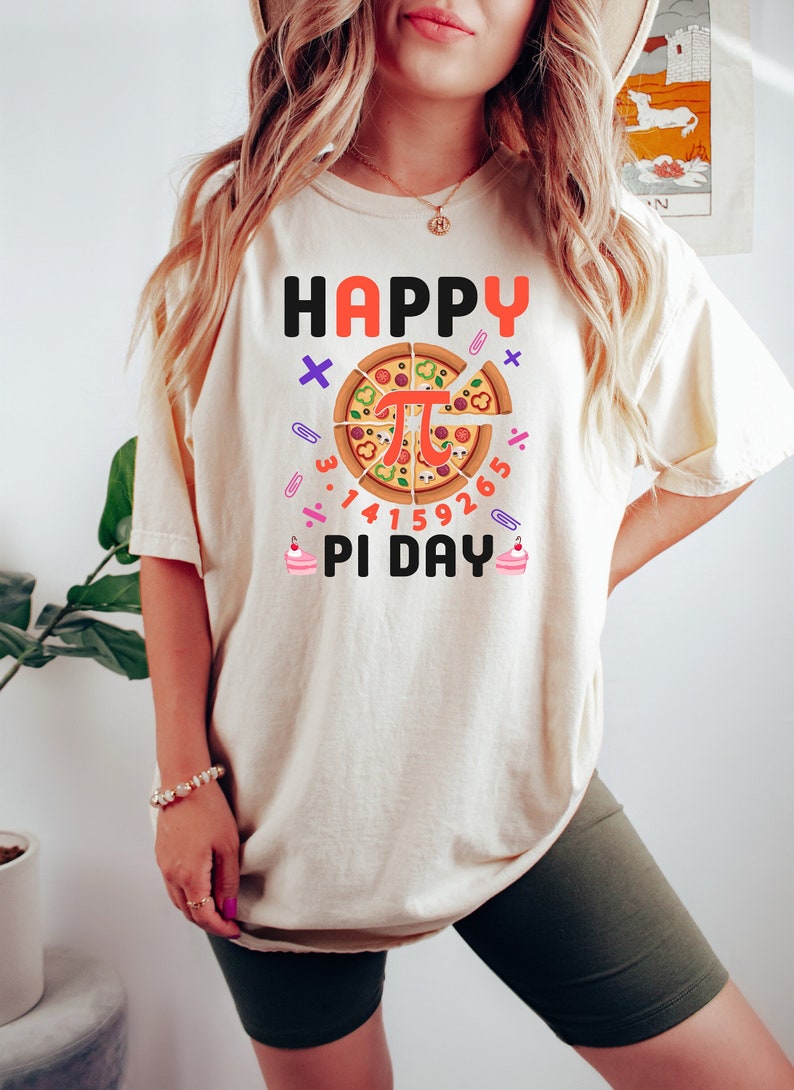 May include: A white t-shirt with the text "HAPPY PI DAY" and a pizza slice with the mathematical symbol for pi in the center. The pizza slice is surrounded by numbers representing the digits of pi.