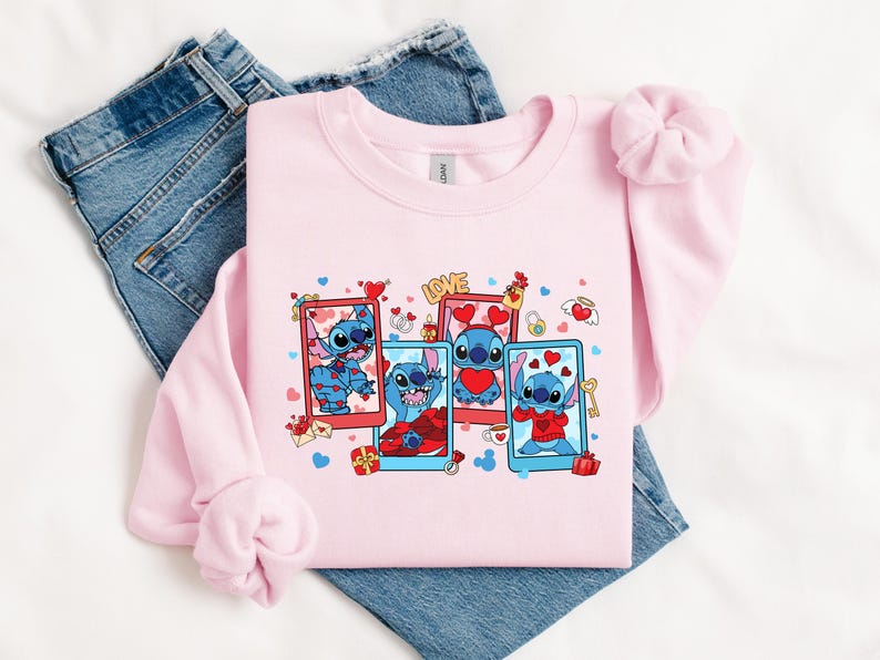 May include: Pink sweatshirt with a graphic print of Stitch from Lilo & Stitch. Stitch is shown in four different poses with hearts and the word "LOVE" on the sweatshirt.