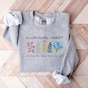 May include: Gray sweatshirt with the text "Occupational Therapy" and a graphic of colorful flowers with the text "Helping you grow your own way".