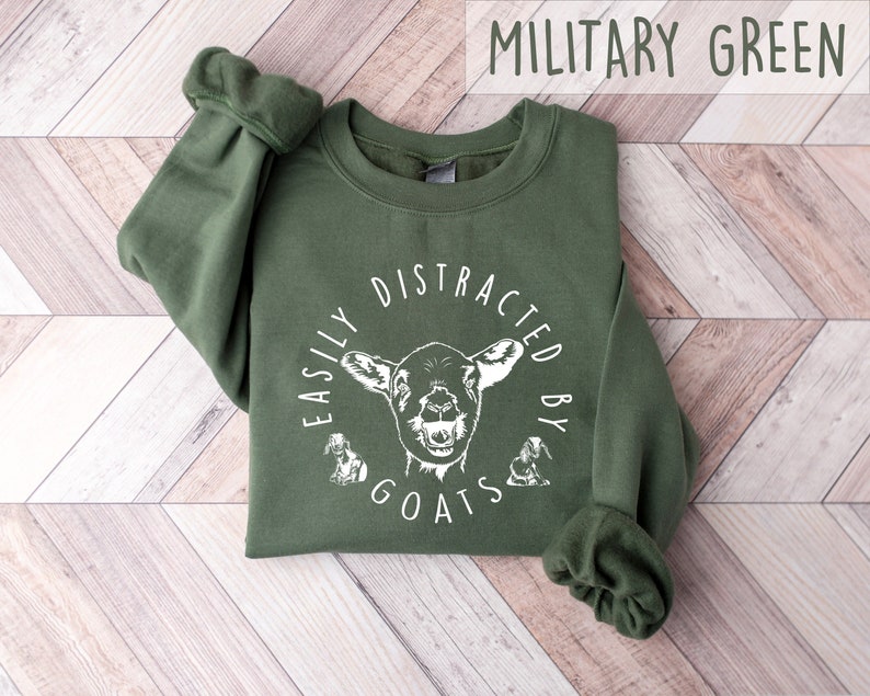 May include: A military green sweatshirt with the text "Easily Distracted by Goats" in white lettering and a white goat illustration.