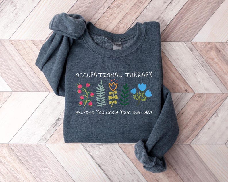 May include: A dark gray sweatshirt with the text "Occupational Therapy" and a graphic of colorful flowers with the text "Helping you grow your own way".