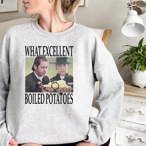 May include: A gray sweatshirt with the text "What Excellent Boiled Potatoes" printed on the front. The text is in black and there is a picture of two men in period clothing holding a bowl of potatoes.