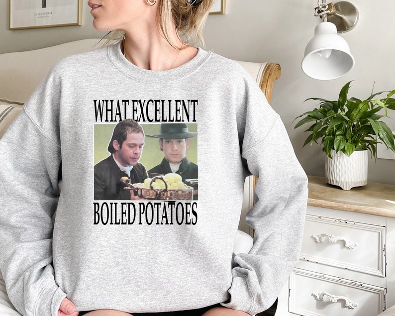 May include: A gray sweatshirt with the text "What Excellent Boiled Potatoes" printed on the front. The text is in black and there is a picture of two men in period clothing holding a bowl of potatoes.