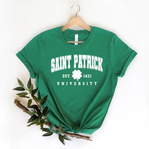 Puede incluir: Camiseta verde con texto blanco que dice "Saint Patrick University Est. 1631" con un gr&aacute;fico de tr&eacute;bol.