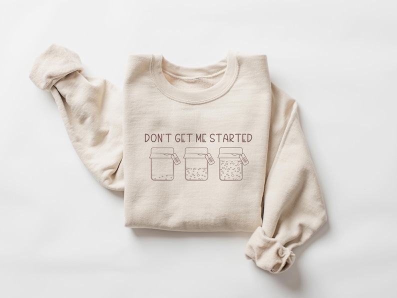 May include: A beige sweatshirt with the text "DON'T GET ME STARTED" and a graphic of three jars with lids.