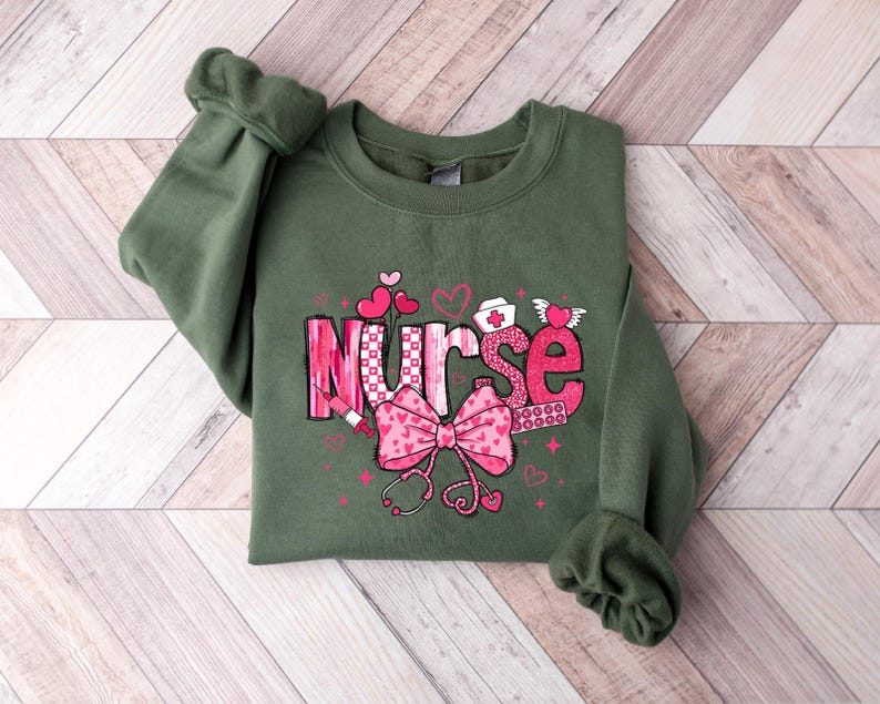 May include: Green sweatshirt with a pink and white graphic that says "Nurse" with hearts, a stethoscope, and a bandage.