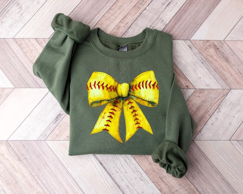 May include: A green sweatshirt with a yellow and red softball bow design.
