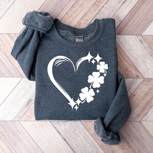May include: A dark gray sweatshirt with a white design of a heart made of shamrocks and stars.