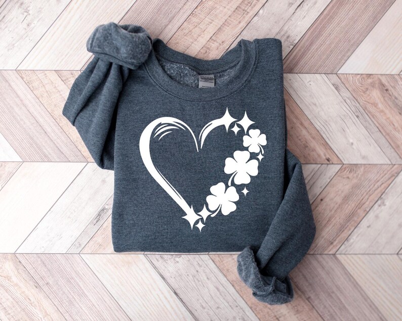 May include: A dark gray sweatshirt with a white design of a heart made of shamrocks and stars.