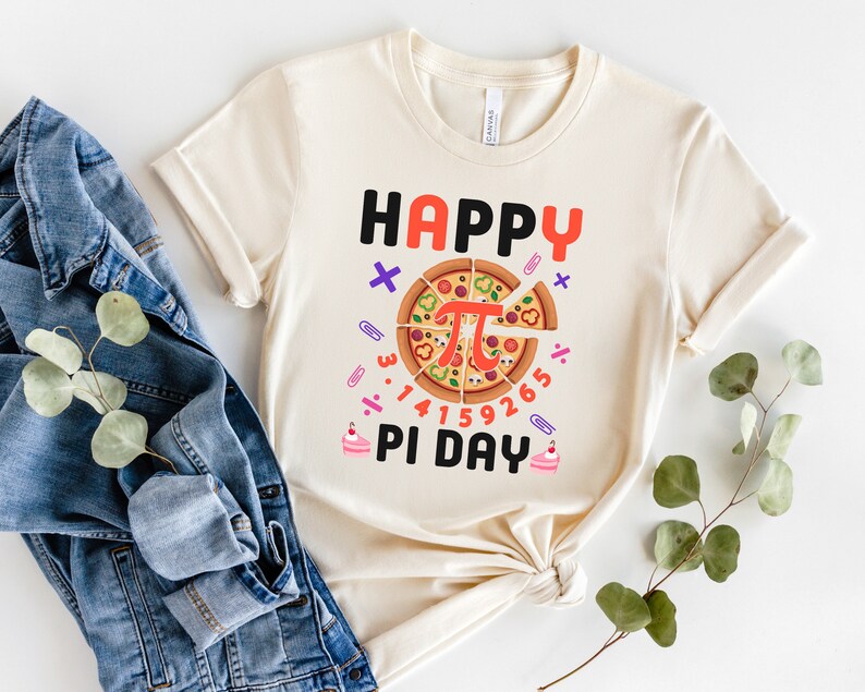 May include: A beige t-shirt with the text "Happy Pi Day" and a pizza slice with the mathematical symbol for pi in the center. The pizza slice is surrounded by numbers and math symbols.