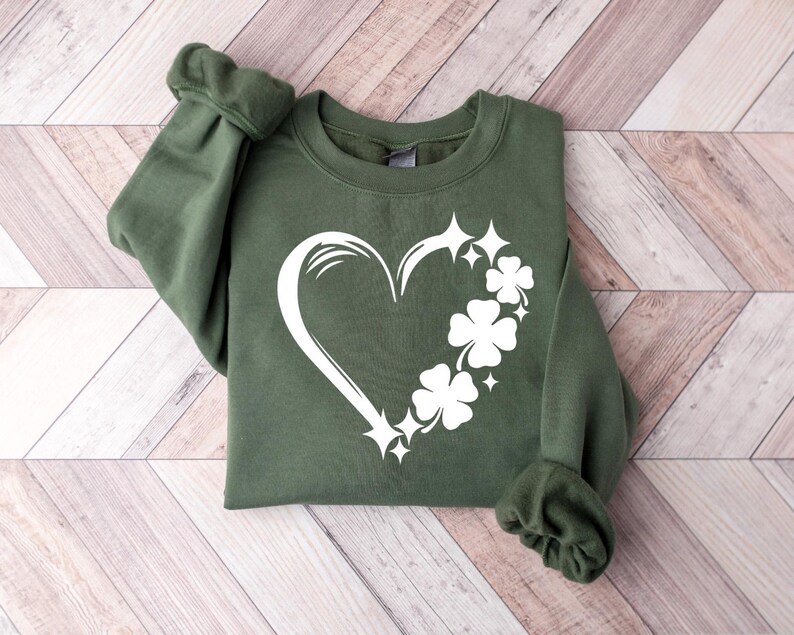 May include: A green sweatshirt with a white heart design featuring four-leaf clovers and sparkling stars.