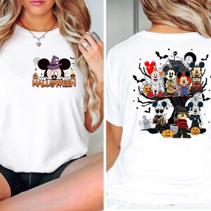 May include: White t-shirt with a Halloween themed graphic featuring Mickey Mouse and other characters. The front of the shirt features Mickey Mouse in a witch's hat with the word "HALLOWEEN" underneath. The back of the shirt features Mickey Mouse and other characters in a spooky tree with pumpkins and bats.