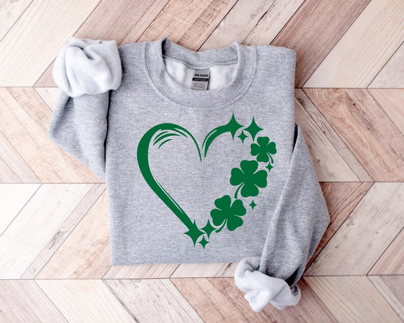 May include: A gray sweatshirt with a green shamrock heart design. The heart is outlined in green and has shamrocks and stars around it.