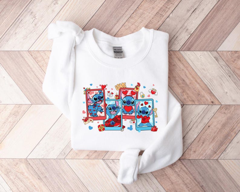 May include: White sweatshirt with a graphic print of Stitch from Lilo & Stitch. The graphic shows Stitch in four different poses with hearts and the word "LOVE".