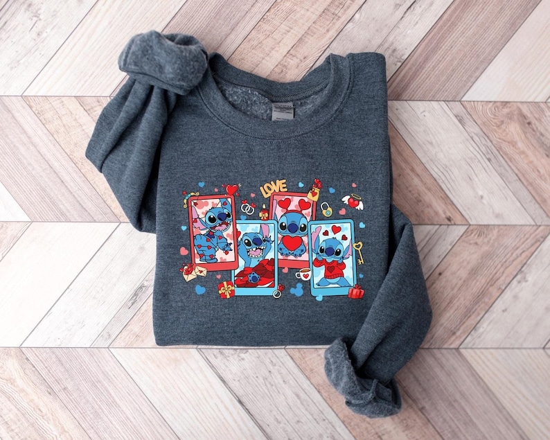 May include: A dark gray sweatshirt with a graphic print of Stitch from Lilo & Stitch. The graphic features Stitch in different poses with hearts and the word "LOVE".