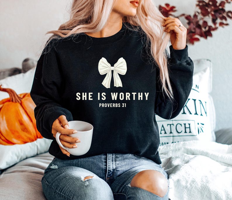 May include: A black sweatshirt with a white bow and the text "She is worthy Proverbs 31" printed on the front.