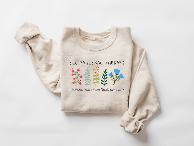May include: A beige sweatshirt with the text "Occupational Therapy" and a graphic of colorful flowers with the text "Helping you grow your own way".