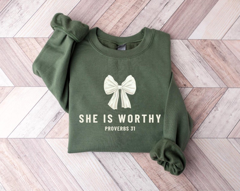May include: A green sweatshirt with a white bow and the text "SHE IS WORTHY PROVERBS 31" printed on the front.