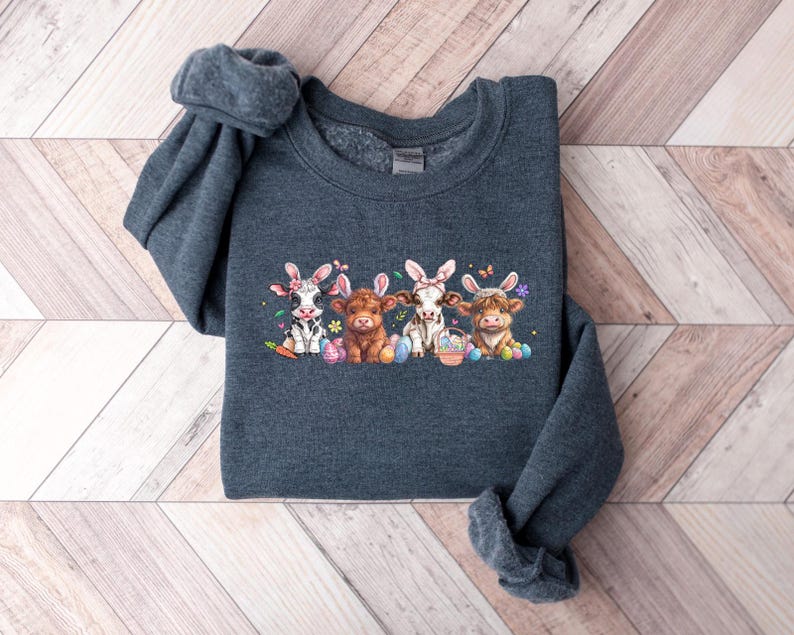 May include: A dark gray sweatshirt with a graphic of four cows wearing bunny ears and holding Easter eggs. The cows are brown, black and white, and have pink noses.