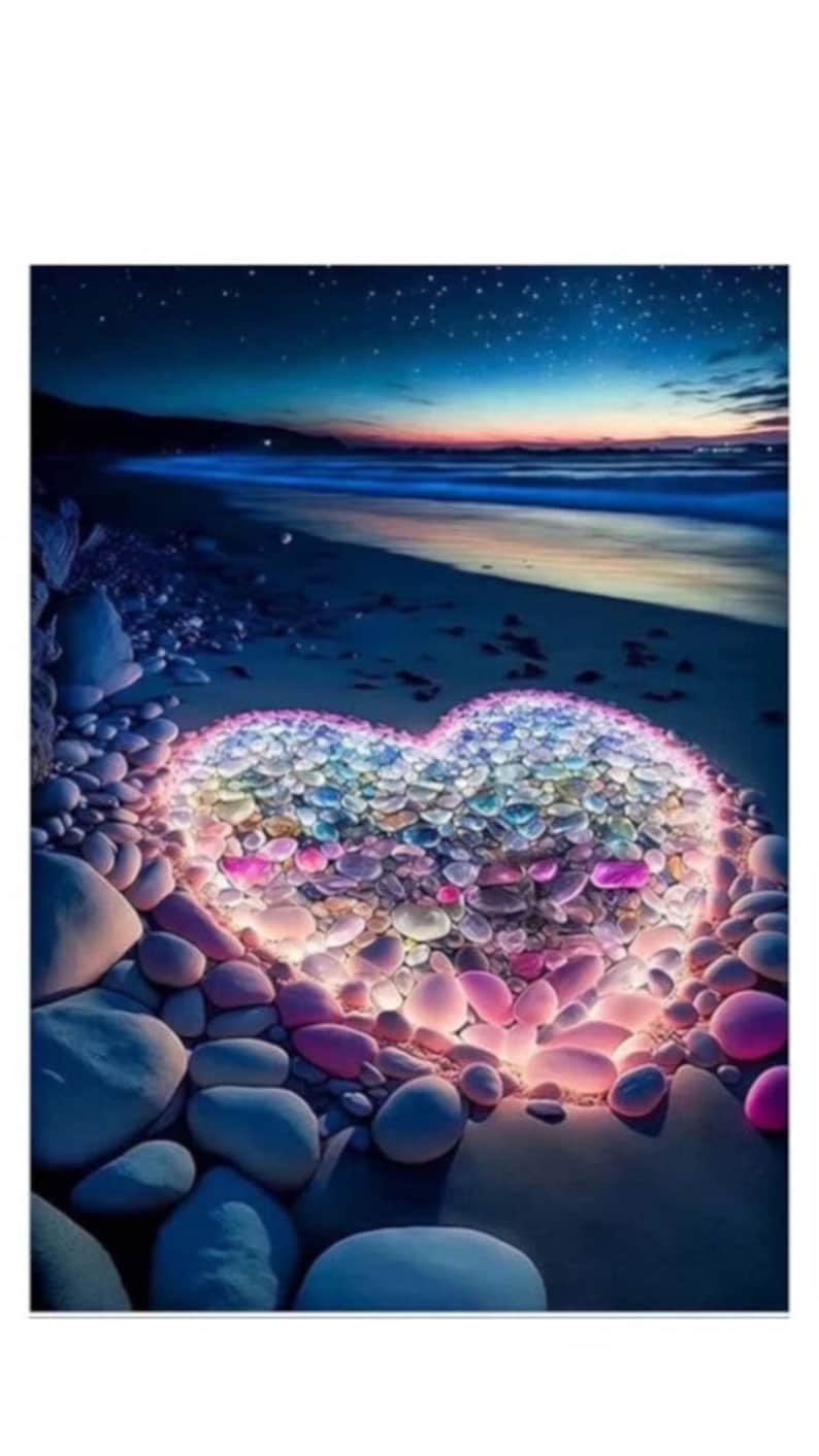 K&ouml;nnte beinhalten: Eine herzf&ouml;rmige Anordnung aus bunten, leuchtenden Steinen an einem Strand in der Abendd&auml;mmerung. Die Steine sind in Rosa, Blau und Wei&szlig; gehalten und strahlen sanft und &auml;therisch. Der Hintergrund zeigt einen Sternenhimmel und das Meer.