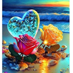 May include: A blue heart-shaped glass orb with a red rose and a yellow rose on a sandy beach with a blue ocean and a sunset sky.