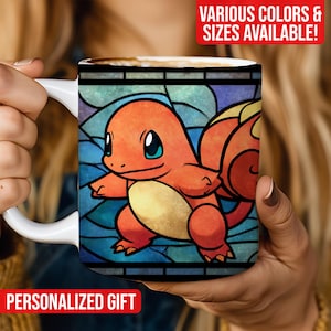 May include: White ceramic mug featuring a colorful illustration of a Charmander character in a stained-glass style. The design includes orange, yellow, and blue hues. Text on the mug reads "PERSONALIZED GIFT" and "VARIOUS COLORS & SIZES AVAILABLE!"