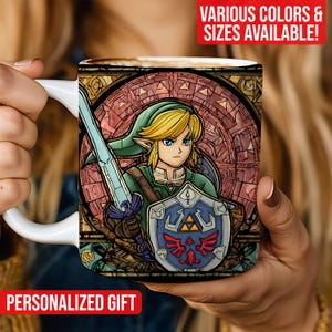 Puede incluir: Taza de cerámica blanca con una ilustración de estilo vidriera de un personaje con una espada y un escudo. El personaje tiene cabello rubio y viste ropa verde. La taza tiene el texto "REGALO PERSONALIZADO" y "¡VARIOS COLORES Y TALLAS DISPONIBLES!"