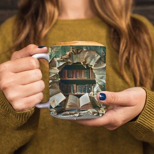 K&ouml;nnte beinhalten: Eine wei&szlig;e Keramiktasse mit einem Design eines B&uuml;cherregals, das &uuml;berquillt mit B&uuml;chern. Die B&uuml;cher sind chaotisch angeordnet und erzeugen so den Eindruck einer literarischen Explosion. Die Tasse wird von den H&auml;nden einer Person gehalten.